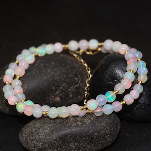 May include: A double strand necklace made of white opal beads with a gold chain clasp.