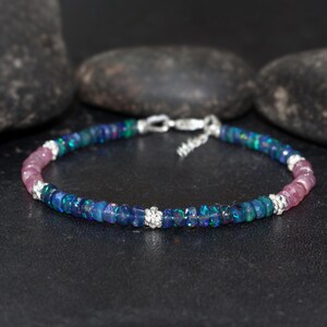 May include: A silver bracelet featuring a graduated design of pink and blue opal beads. The bracelet has a silver clasp.