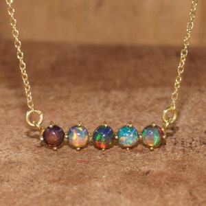 May include: A gold chain necklace with five round, iridescent opal stones set in gold.