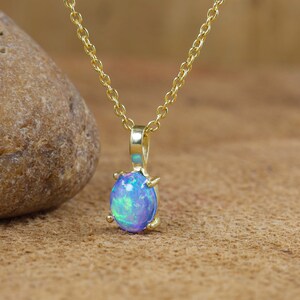 May include: A gold chain necklace with a blue opal pendant. The opal is set in a gold bezel.