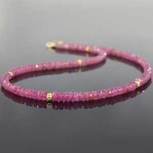 May include: A pink gemstone necklace with gold accents. The necklace is made of small, faceted beads and is strung on a delicate chain.