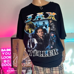 Puede incluir: Camiseta negra con un estampado gr&aacute;fico de Jax Teller de la serie de televisi&oacute;n Sons of Anarchy. El gr&aacute;fico es un collage de im&aacute;genes de Jax Teller y otros personajes de la serie.