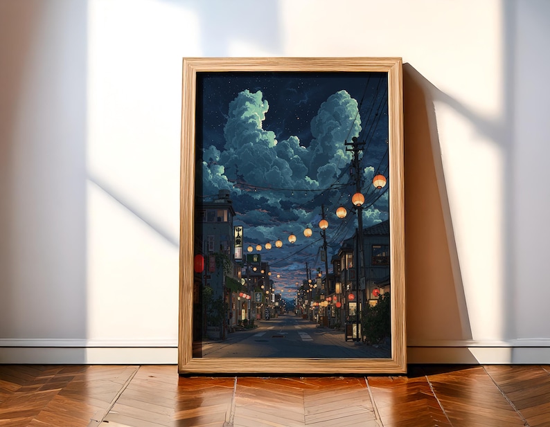 May include: A framed art print depicts a nighttime street scene with glowing lanterns strung overhead. The artwork features a detailed illustration of buildings, a road, and dramatic cloud formations in a palette of blues, oranges, and yellows.