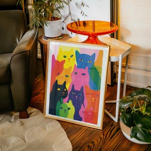 May include: A framed art print featuring a colorful illustration of numerous cats. The cats are depicted in various vibrant colors, including yellow, pink, blue, and green, with black outlines. The artwork is set against a white background and framed in gold.