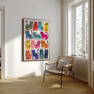 K&ouml;nnte beinhalten: Ein gerahmter Kunstdruck mit einem Raster aus farbenfrohen Katzenillustrationen. Jede Katze ist in einer einzigartigen Pose und Farbpalette dargestellt, darunter Blau-, Rot-, Gelb- und Rosat&ouml;ne. Das Kunstwerk wird an einer wei&szlig;en Wand pr&auml;sentiert.