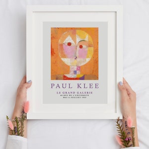 May include: A framed poster featuring a colorful abstract painting by Paul Klee. The painting depicts a stylized face with geometric shapes and vibrant colors. The poster includes the title "Paul Klee" and the text "Le Grand Galerie 60 Rue de l'Universite Mai a Juillet 1955."