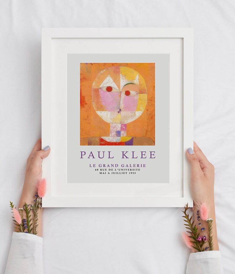 May include: A framed poster featuring a colorful abstract painting by Paul Klee. The painting depicts a stylized face with geometric shapes and vibrant colors. The poster includes the title "Paul Klee" and the text "Le Grand Galerie 60 Rue de l'Universite Mai a Juillet 1955."