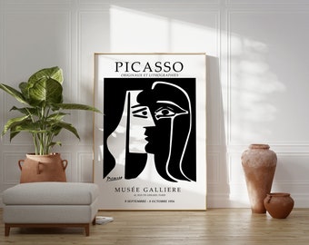 May include: Black and white poster with a minimalist line drawing of a woman's face. The poster is framed in gold and has the text "PICASSO ORIGINAUX ET LITHOGRAPHIES" at the top and "MUSÉE GALLIERE 6, RUE DE SEINE, PARIS 9 SEPTEMBRE - 8 OCTOBRE 1956" at the bottom.