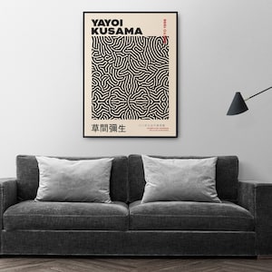 May include: A black and white poster with a geometric pattern and the text "YAYOI KUSAMA 1929-2018" and "草間彌生" in Japanese. The poster is framed and hanging on a white wall.