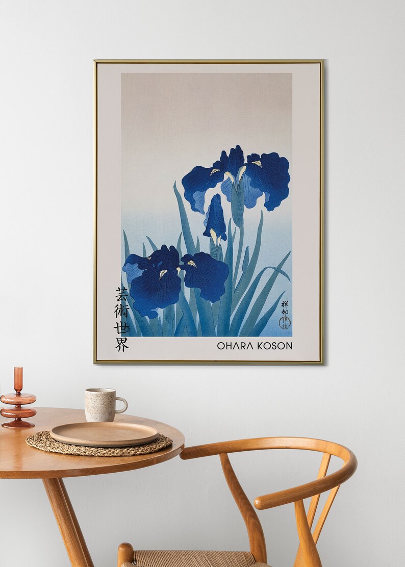 May include: A framed print of a Japanese painting featuring blue irises with green leaves. The artist's signature is in the bottom right corner, and the title "春艸界" is in the bottom left corner. The artist's name "OHARA KOSON" is printed below the signature.