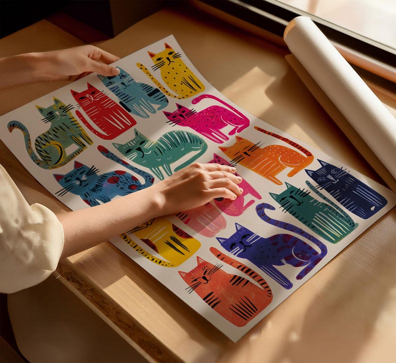 K&ouml;nnte beinhalten: Ein farbenfroher Kunstdruck mit einem sich wiederholenden Muster stilisierter Katzen in verschiedenen Farben, darunter Gelb, Rot, Blau und Pink. Der Druck wird auf einer Holzoberfl&auml;che pr&auml;sentiert, mit einer aufgerollten Posterrolle im Hintergrund.