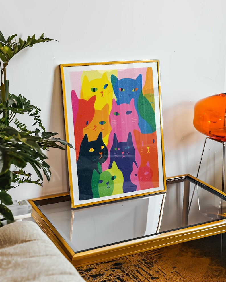 May include: A framed art print featuring a colorful illustration of multiple cats. The cats are depicted in various vibrant colors, including yellow, blue, pink, and green. The artwork is displayed in a gold frame, adding a touch of elegance.