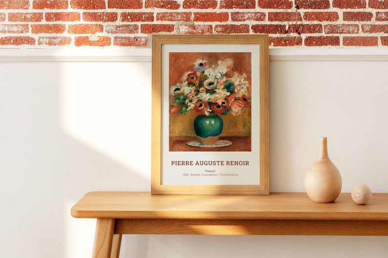 Op de afbeelding: Een ingelijste print van een schilderij van Pierre Auguste Renoir met de titel "Bloemen". Het schilderij toont een boeket kleurrijke bloemen in een groene vaas op een wit bord. Het schilderij is ingelijst in een lichtbruin houten lijst.