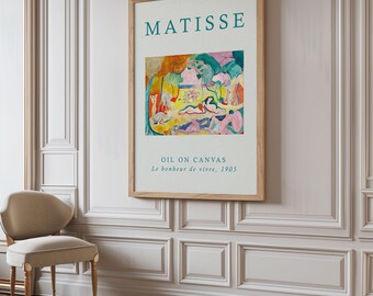 May include: A framed poster with a painting by Henri Matisse titled "Le bonheur de vivre" (The Joy of Life). The painting depicts a group of people in a landscape setting with vibrant colors and a whimsical style. The poster also includes the text "MATISSE" and "OIL ON CANVAS, Le bonheur de vivre, 1905."