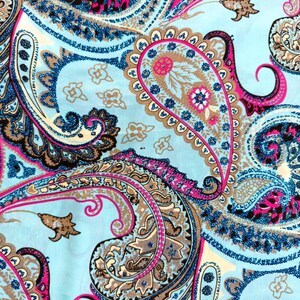 May include: A close-up of a fabric with a paisley pattern. The design features large, swirling paisley shapes in shades of blue, pink, brown, and white against a light blue background. The pattern is detailed and intricate, with a mix of solid and dotted lines.