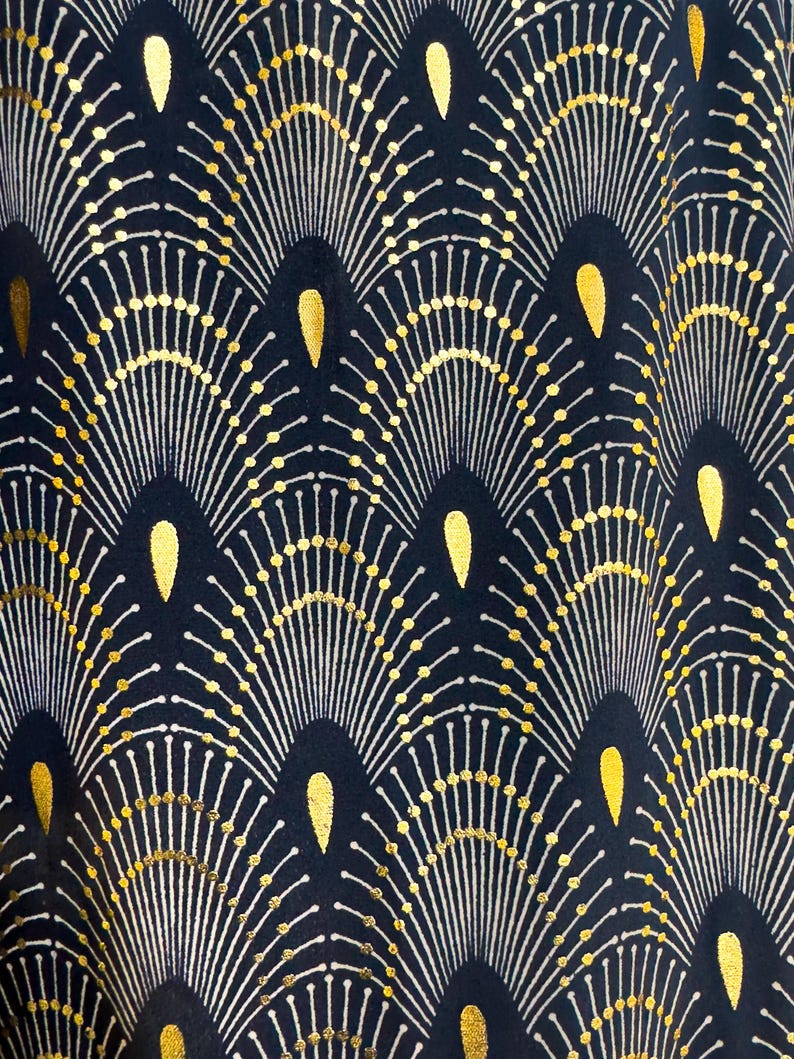 May include: A navy blue fabric with a repeating pattern of gold and white stylized sunbursts. The sunbursts are arranged in a wave-like pattern.