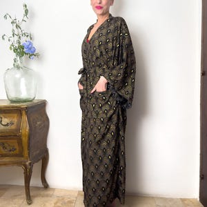 May include: A long, black and gold patterned robe with a wide, flowing sleeve. The robe has a belt and pockets.