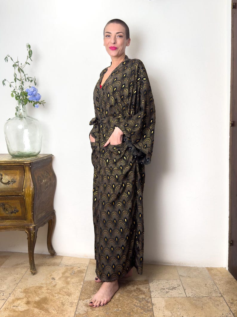 May include: A long, black and gold patterned robe with a wide, flowing sleeve. The robe has a belt and pockets.