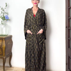 May include: A long black and gold robe with a peacock feather pattern. The robe has pockets on the sides and a tie belt.