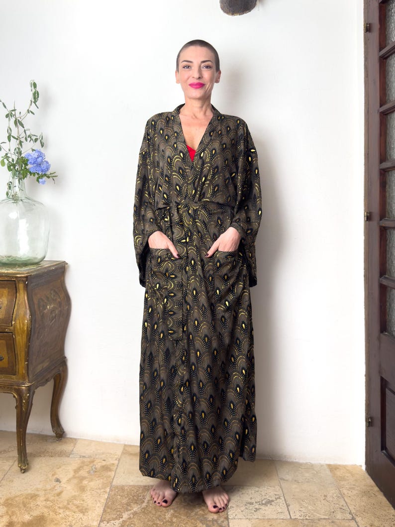 May include: A long black and gold robe with a peacock feather pattern. The robe has pockets on the sides and a tie belt.
