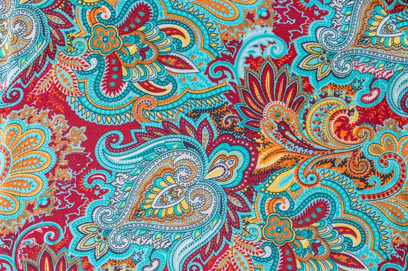 May include: A colorful paisley pattern fabric with a turquoise, red, orange, and yellow color scheme. The fabric has a repeating pattern of paisley shapes and floral designs.