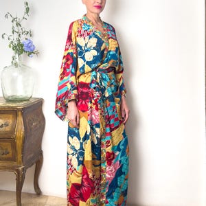 May include: A long, colourful floral print robe with a tie belt. The robe has a blue, yellow, red, and pink floral pattern.