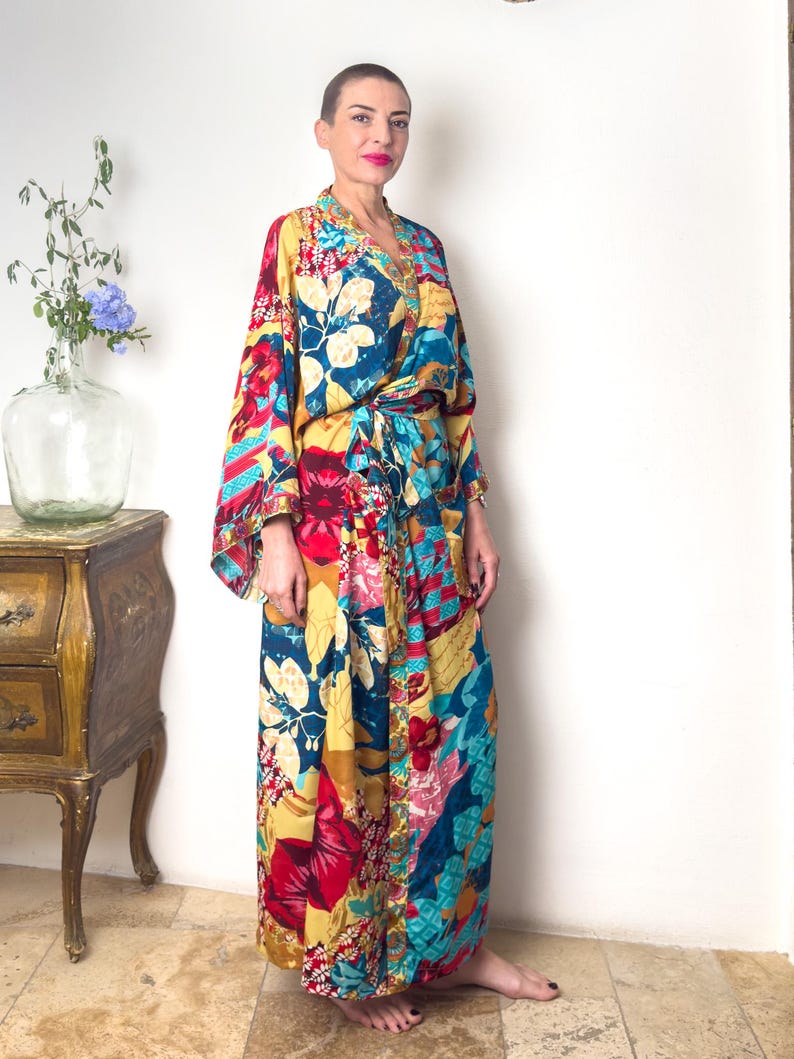 May include: A long, colourful floral print robe with a tie belt. The robe has a blue, yellow, red, and pink floral pattern.