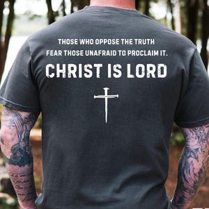 May include: A dark gray t-shirt with a white cross and the text "Those who oppose the truth fear those unafraid to proclaim it. Christ is Lord."