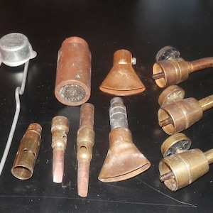 Collection of antique propane torch accessories including 3 valve/tip assemblies, 6 assorted torch tips, spark striker, and 2 copper brushes
