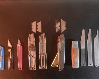 Collection of old utility knives with replaceable blades. Lots of sharp edges for cutting and trimming, most blades have not been used.