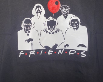 May include: Black t-shirt with a white silhouette of five horror movie characters, including a clown, a ghost, and a hockey mask-wearing killer. The characters are arranged in a line with a red balloon above them. The text "FRIENDS" is printed below the characters.