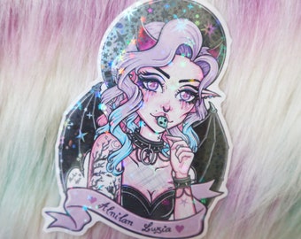 May include: A holographic sticker featuring a stylized illustration of a female demon with purple hair, horns, and bat wings. She is holding a skull lollipop. The sticker has the text "Alnilan Luzia" on a banner.