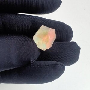 Puede incluir: Un peque&ntilde;o cristal transl&uacute;cido rosa y verde con una forma irregular y rugosa.
