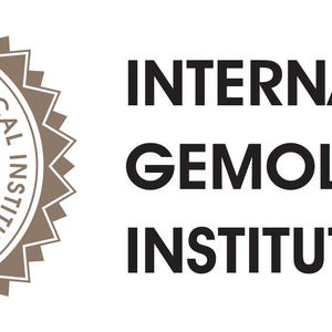May include: The International Gemological Institute logo, featuring a diamond shape within a circular emblem, with the text "INTERNATIONAL GEMOLOGICAL INSTITUTE" and "1975". The logo is in shades of brown and white.