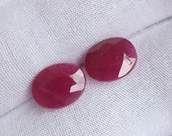 Puede incluir: Dos piedras preciosas ovaladas de color rosa intenso con una superficie lisa y pulida.