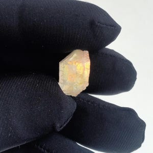 Puede incluir: Un cristal transparente y facetado con un brillo dorado. El cristal es de color amarillo claro y tiene una textura rugosa y natural.
