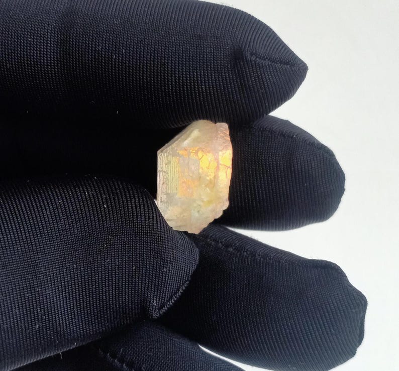 Puede incluir: Un cristal transparente y facetado con un brillo dorado. El cristal es de color amarillo claro y tiene una textura rugosa y natural.