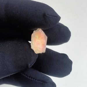 Puede incluir: Un peque&ntilde;o cristal transl&uacute;cido rosa y amarillo con una superficie rugosa y facetada.