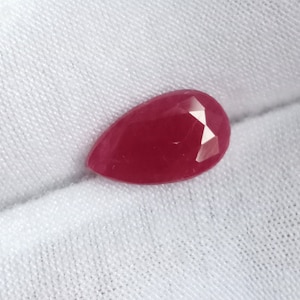 Puede incluir: Una piedra preciosa de rubí de forma de pera, facetada, de color rojo intenso.