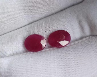 Puede incluir: Dos piedras preciosas de color rojo rubí, de forma ovalada y facetadas.