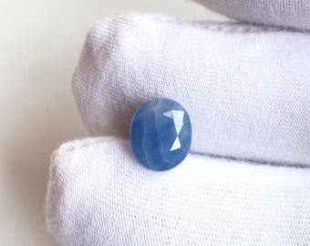 May include: A round, faceted, light blue gemstone. The gem has a star-like pattern on its surface. The stone is set against a white background.