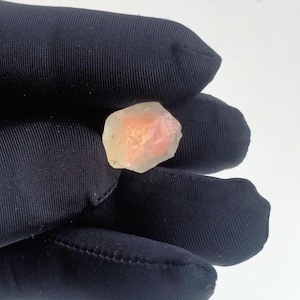 Puede incluir: Un cristal transl&uacute;cido de color rosa claro y blanco con una forma irregular y rugosa.