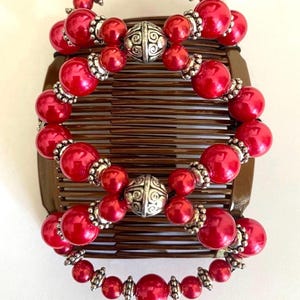 May include: Ornate red hair combs with brown bases. The combs are adorned with red beads and silver-colored accents. The text "Ornate Red with Brown Combs" is visible at the bottom of the image.