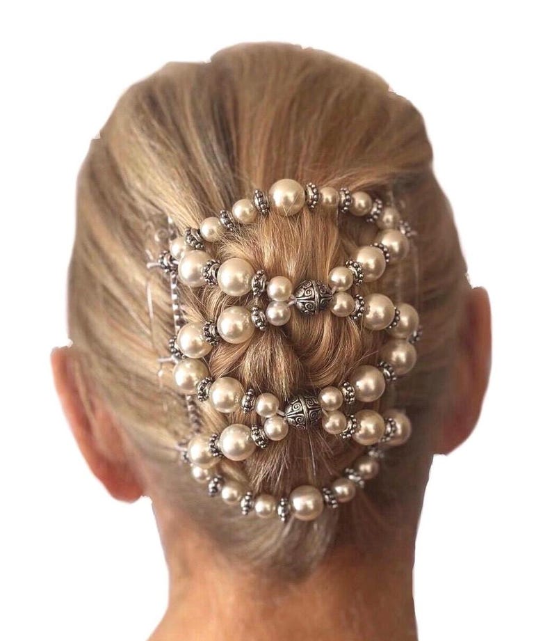May include: An elegant hair accessory featuring multiple strands of faux pearls and silver-toned metal accents. The design is arranged in a circular pattern, creating a sophisticated look. This hairpiece is suitable for special occasions.