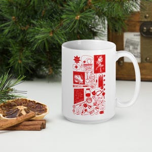 May include: White ceramic mug with a red design featuring a variety of illustrations, including a shoe, a shovel, a bottle, a key, and a star. The design is reminiscent of a collage.