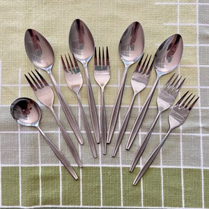 May include: A set of nine silver-toned utensils, including spoons and forks, arranged in a fan shape on a green and white checkered tablecloth.