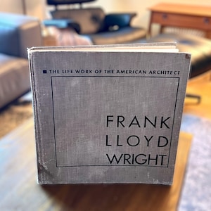 May include: A gray hardcover book with the title "The Life Work of the American Architect Frank Lloyd Wright" printed on the front cover.