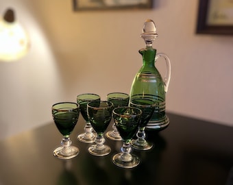Puede incluir: Un juego de seis vasos de chupito de vidrio verde con ribetes dorados y una jarra de vidrio verde a juego con un tapón dorado.