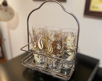 Puede incluir: Un juego de seis vasos vintage de vidrio con un diseño floral marrón y amarillo, en un estante de alambre cromado.