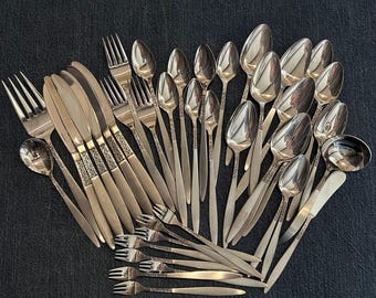 May include: A set of silverware with a floral pattern on the handles. The set includes forks, knives, spoons, and a serving spoon. The silverware is made of stainless steel and has a polished finish.